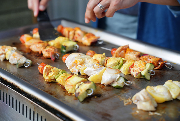 Person using flat top grill bbq cooking kabobs